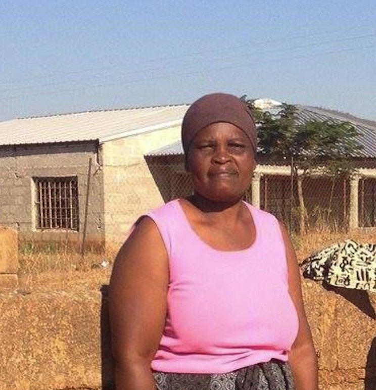 A black woman smiling at the camera in a rural environment